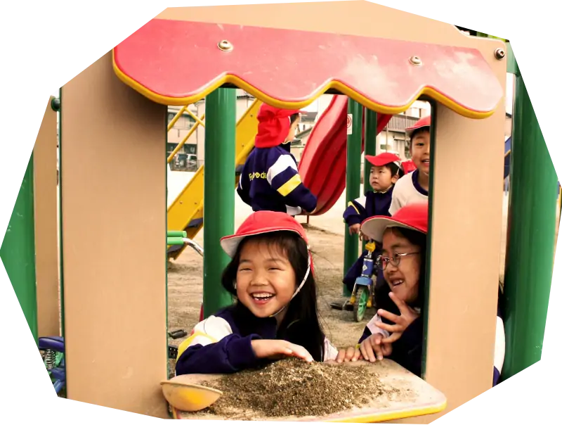 遊具と砂で遊ぶ幼稚園児